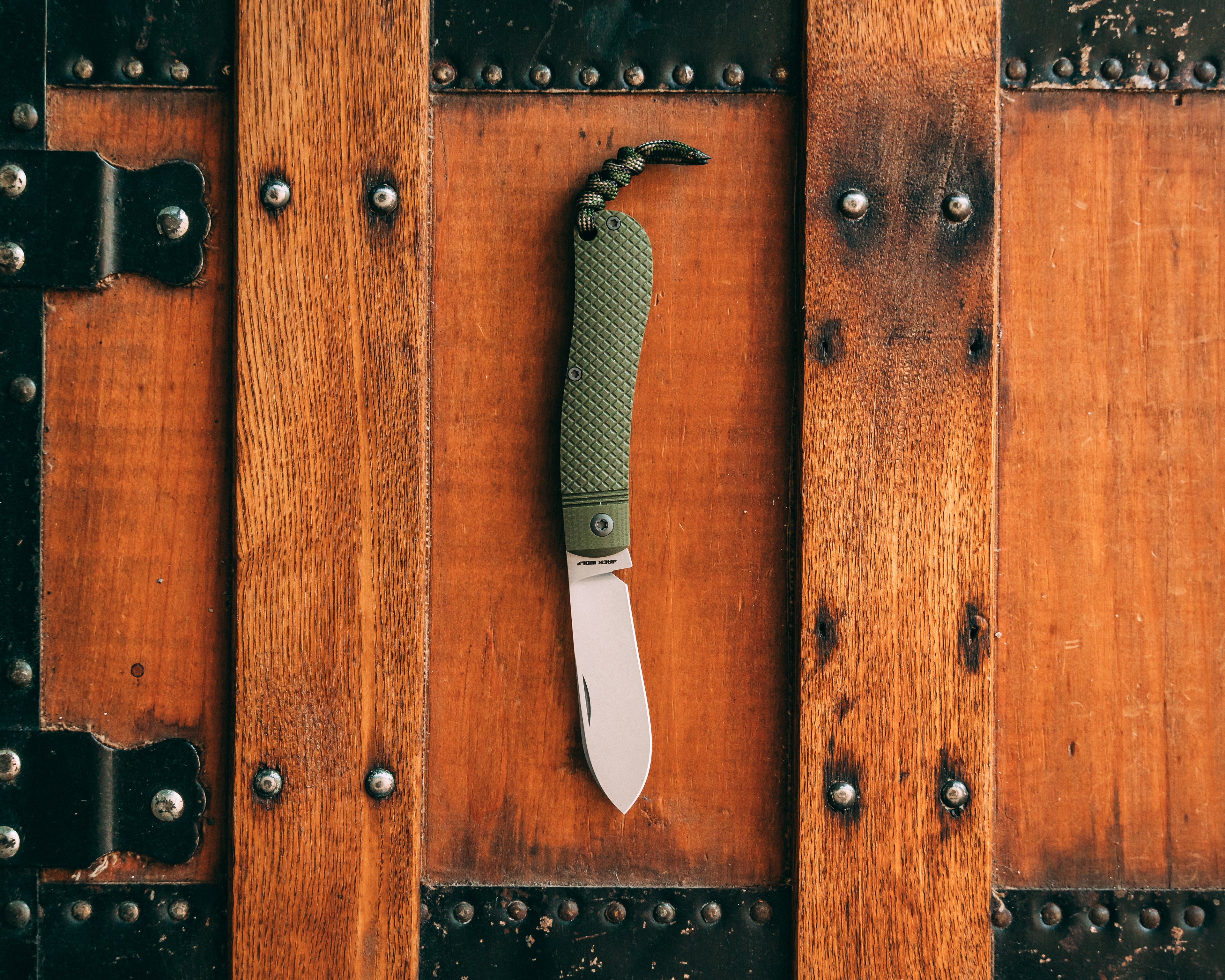 Folding knife with green handle on a wooden surface