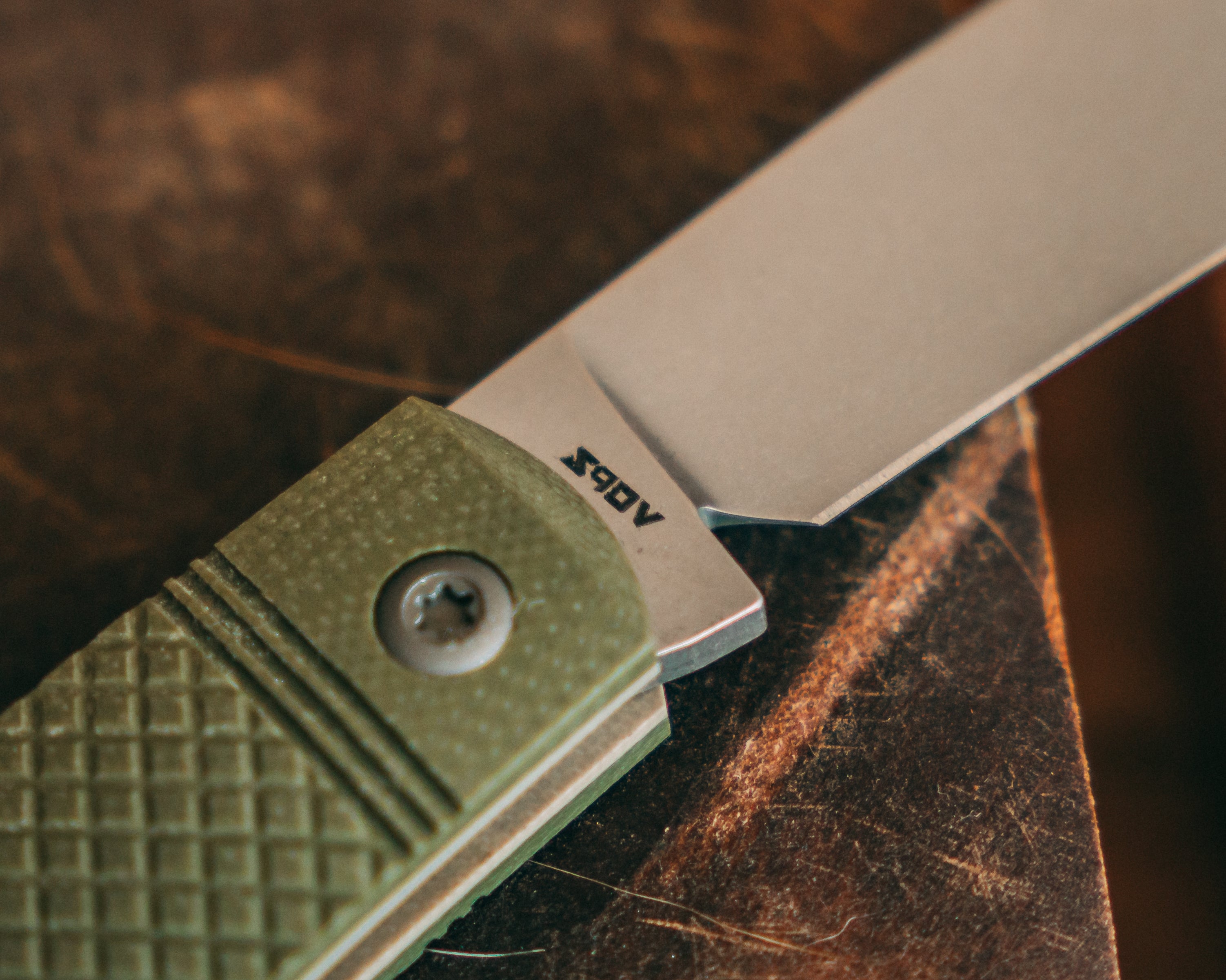 Folding knife with a green handle on a wooden surface