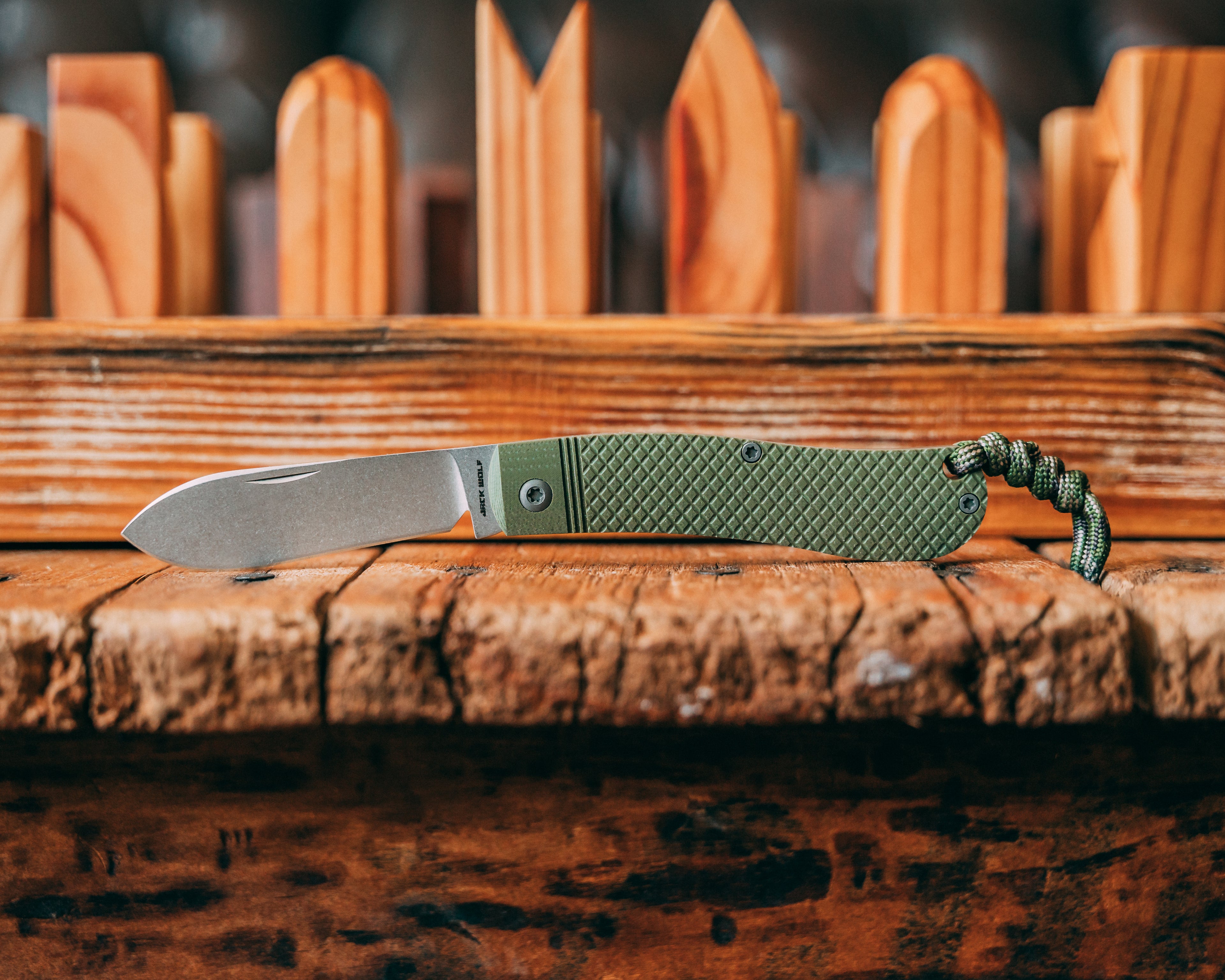 Green folding knife with a textured handle on a wooden surface