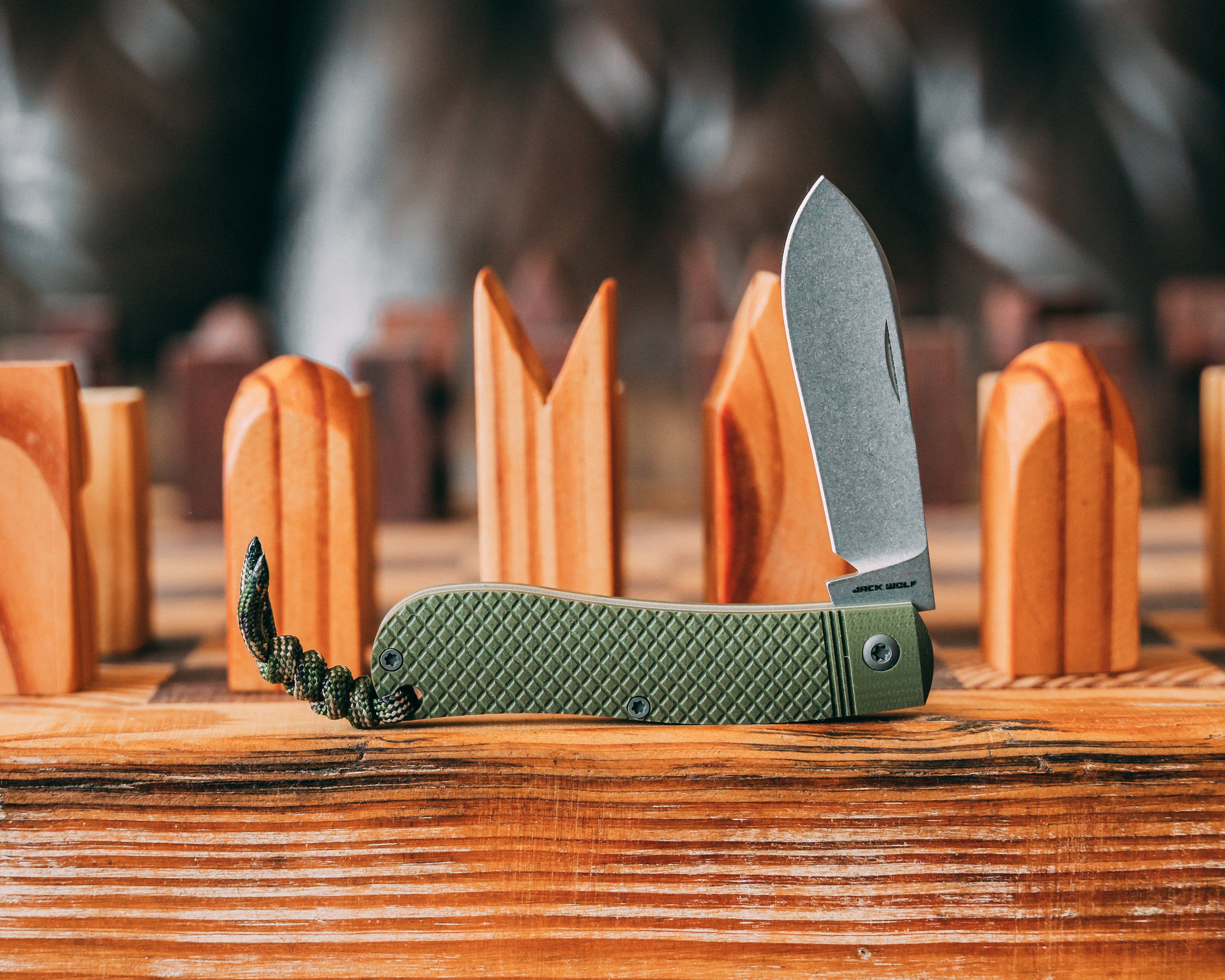 Green pocket knife with textured handle on a wooden surface