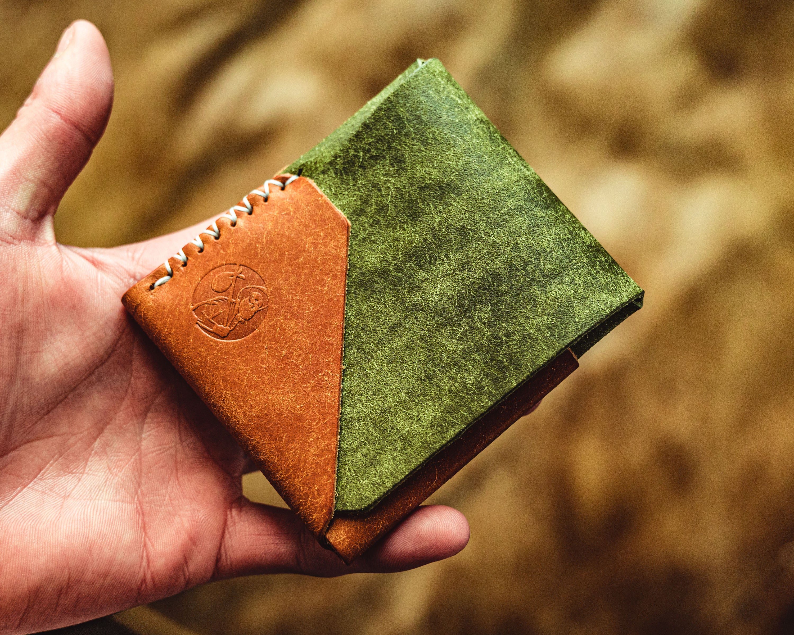 Carry Commission / Open Sea Leather Houbei 2.0 held in hand front view set against a khaki background