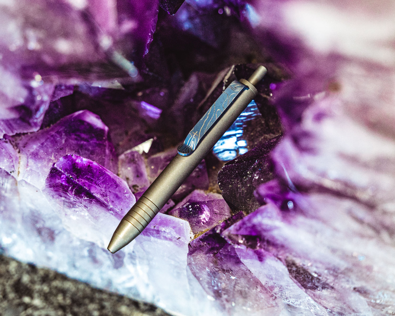Titanium Carry Commission & Big Idea Design mini click pen sitting on purple and white geode