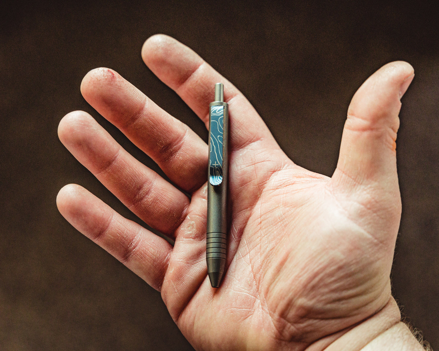 Titanium Carry Commission & Big Idea Design mini click pen placed in open hand
