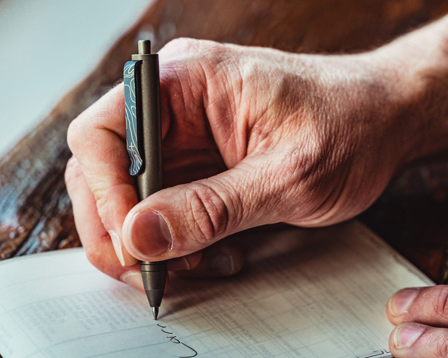 Titanium Carry Commission & Big Idea Design mini click pen in a hand writing on paper