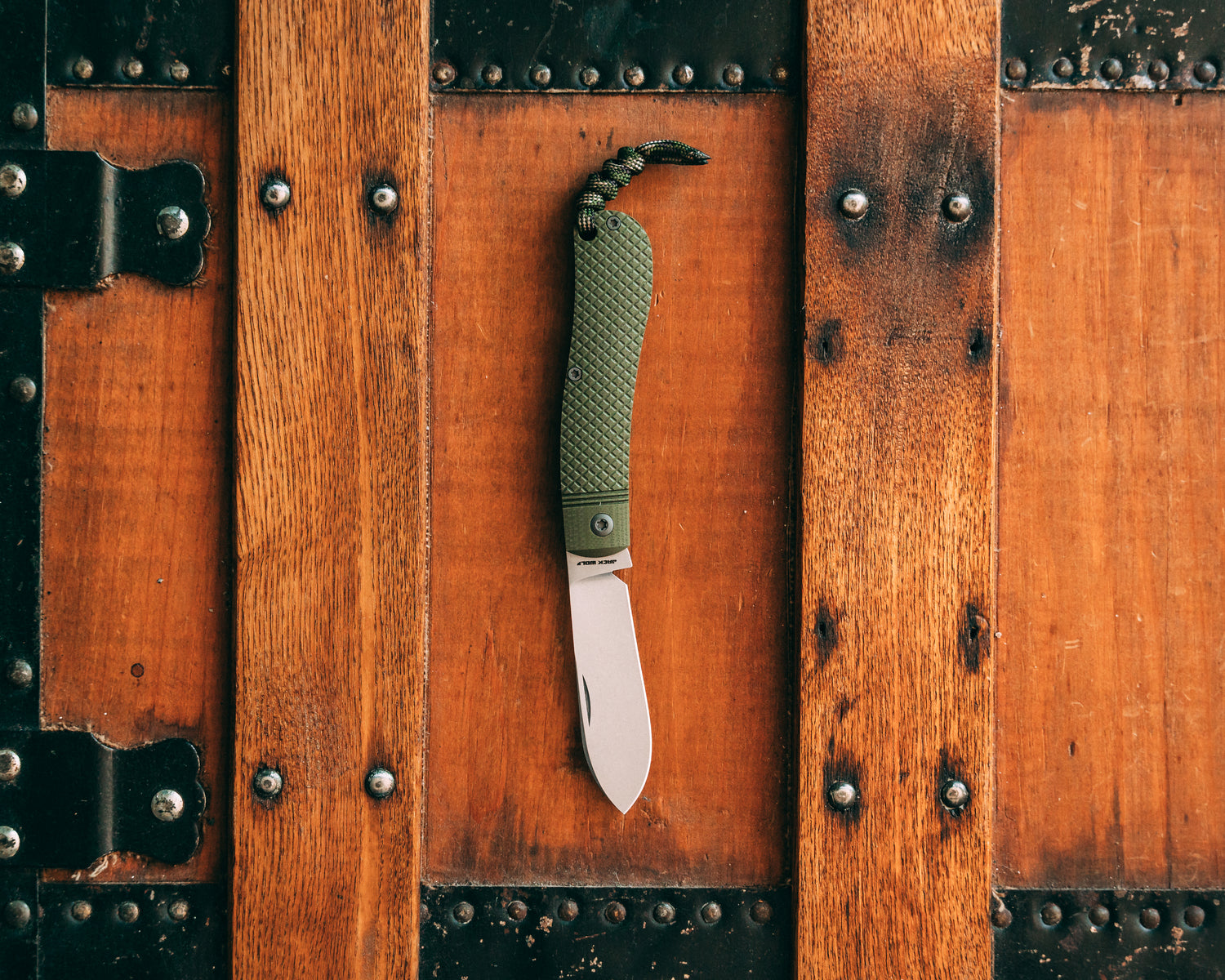 Folding knife with green handle on a wooden surface