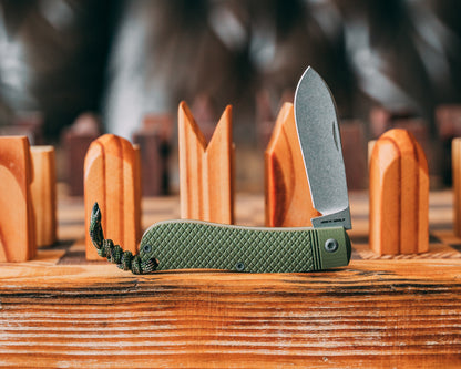 Green pocket knife with textured handle on a wooden surface