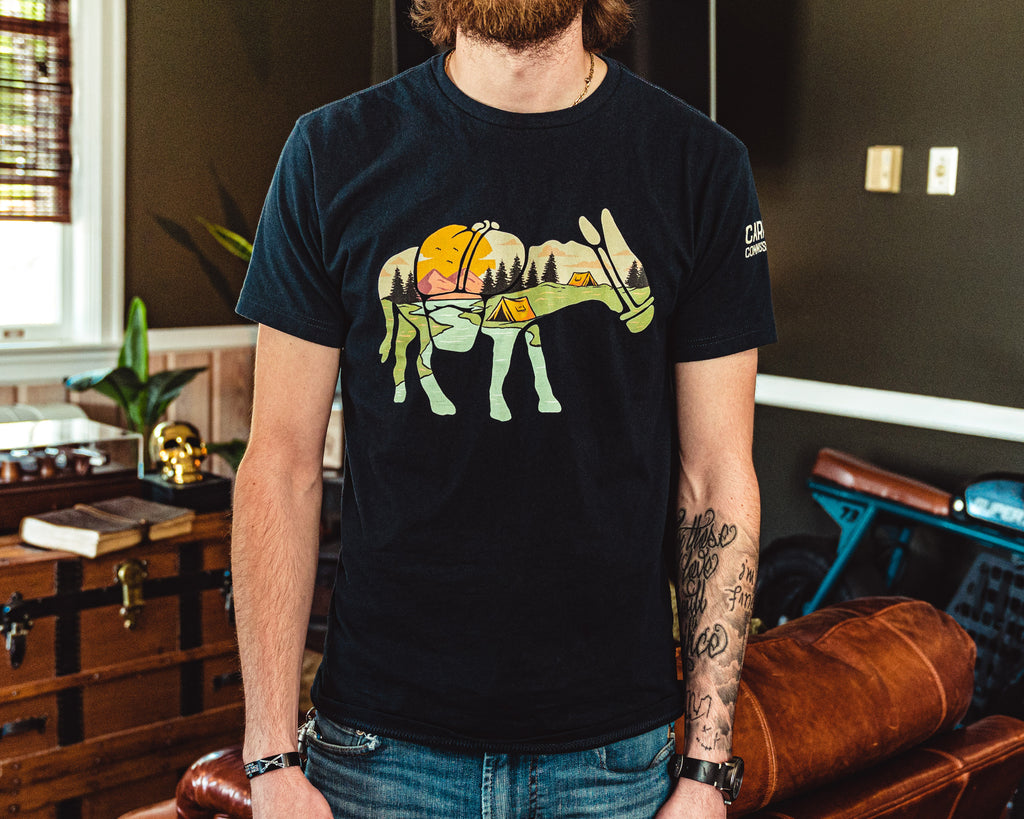 Front view of man wearing a navy color t-shirt featuring a camping landscape scene inside a donkey silhouette.