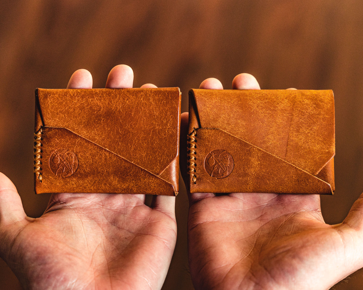 Two Carry Commission / Open Sea Leather Gun Deck Minis in cognac side by side showing a new and a used wallet and the patina differential