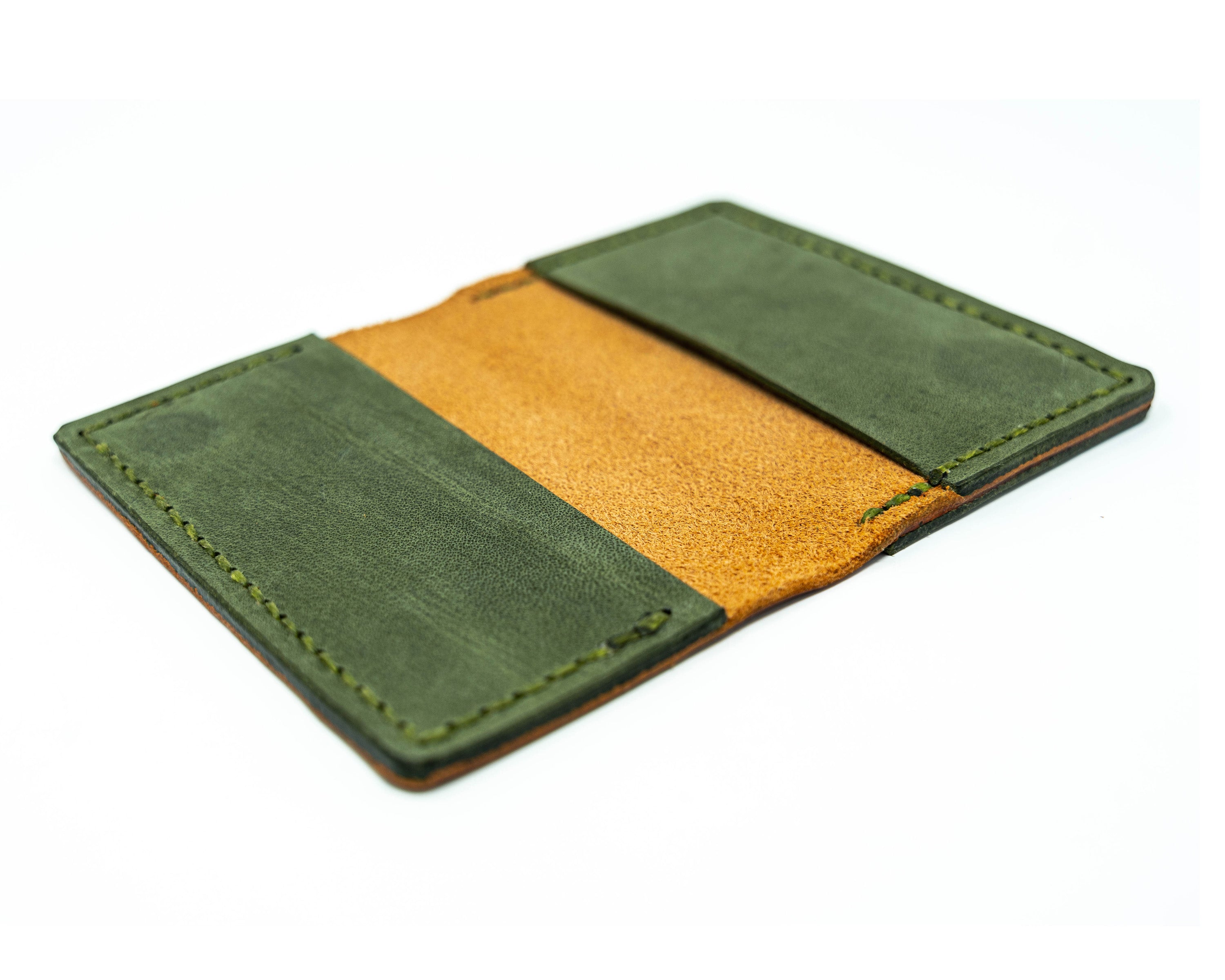 Offset overhead view of an open brown and green bifold wallet on a white background