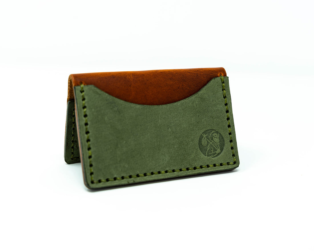 View of bifold brown and green wallet in a &quot;tent&quot; shape on a white background