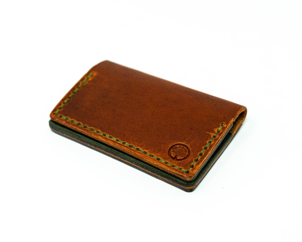 Offset top view of bifold brown and green wallet on a white background