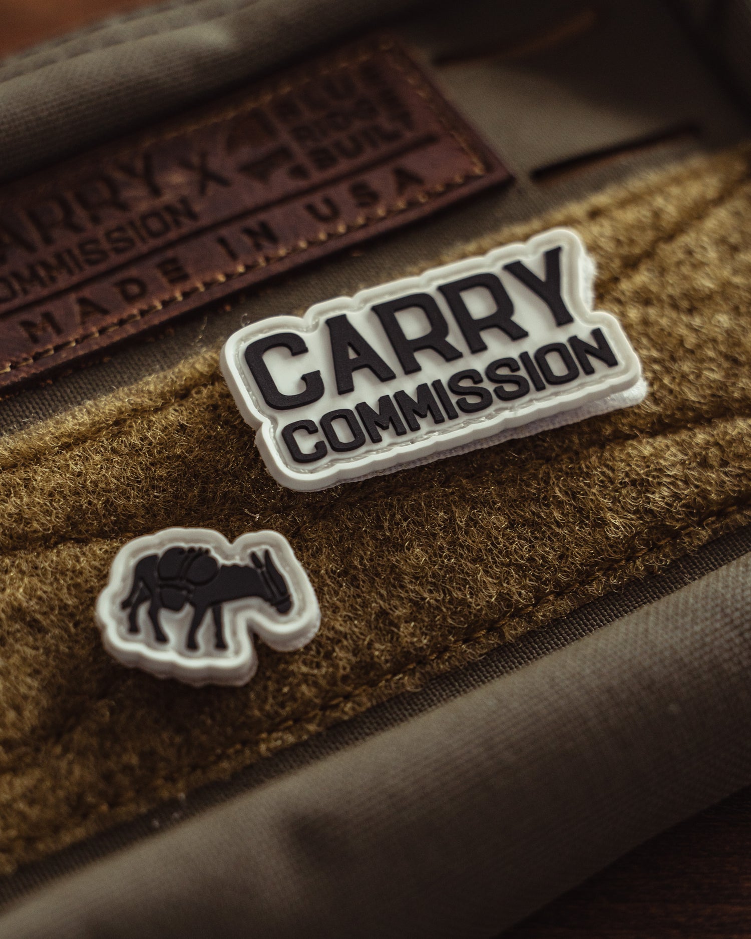 Glow in the dark ranger eye patches of a donkey and the Carry Commission Logo attached to a tan hook and loop on a bag.