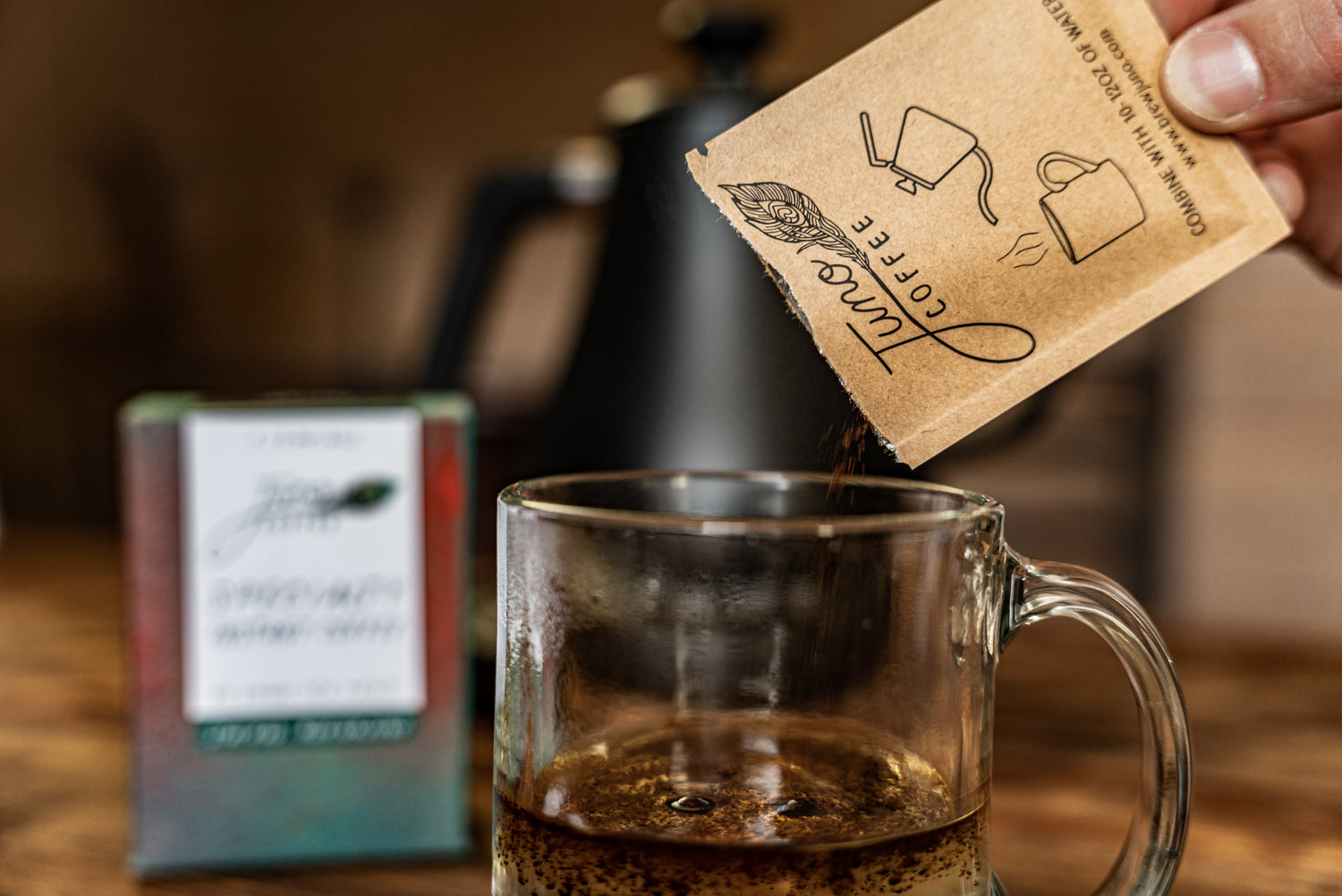 Packet of Juno Specialty Instant Coffee being poured into a clear coffee cup.