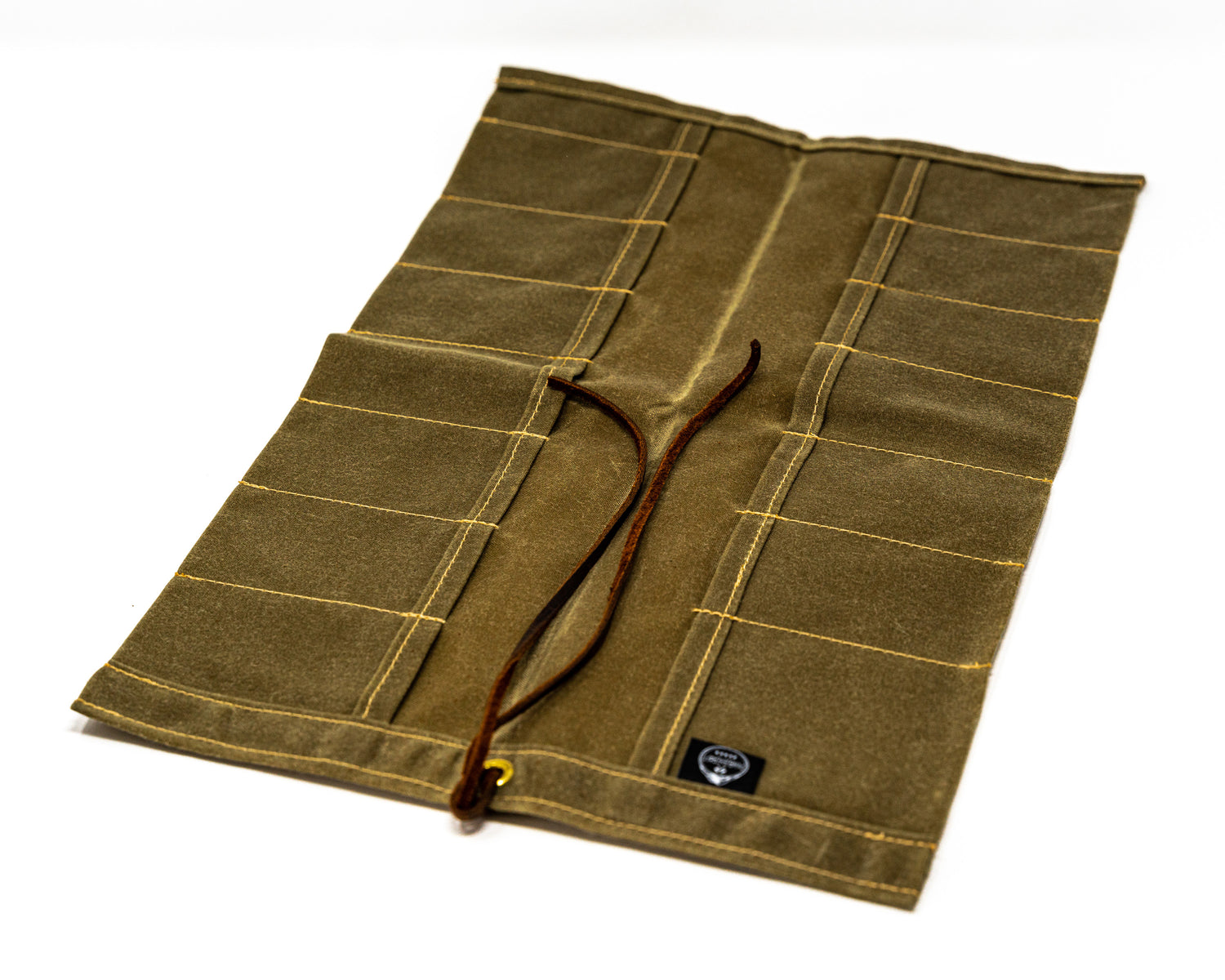 Open PNW Bushcraft Maple Waxed Canvas Knife Roll in Tan positioned at an angle on a white background.