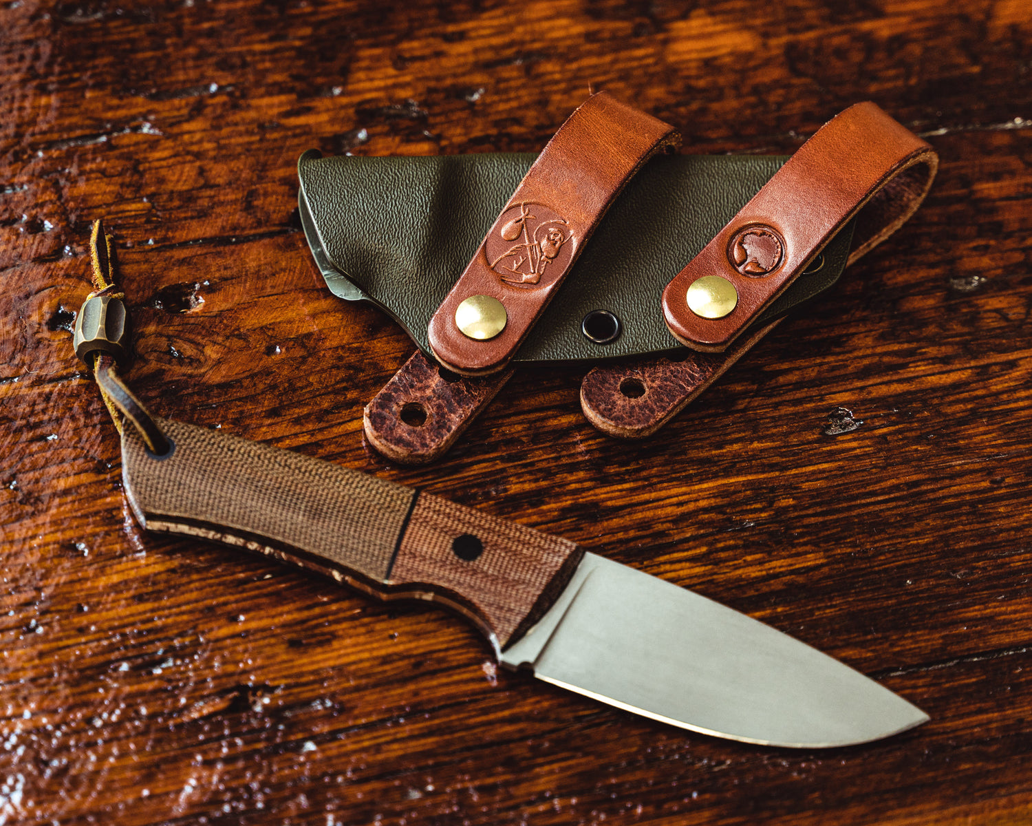 Carry Commission / Redeemed Creations Scout Straps attached to knife sheath with knife overhead view on wooden background