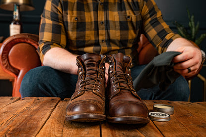 Pair of leather boots in foreground on wooden table with Smith&