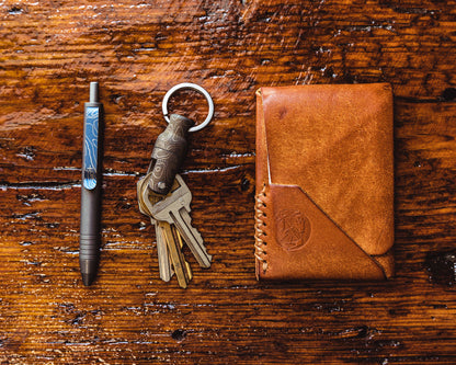 Carry Commission / Urban Carvers Keyper MQR Bronze Topo with keys, a pen and a wallet on a wooden background
