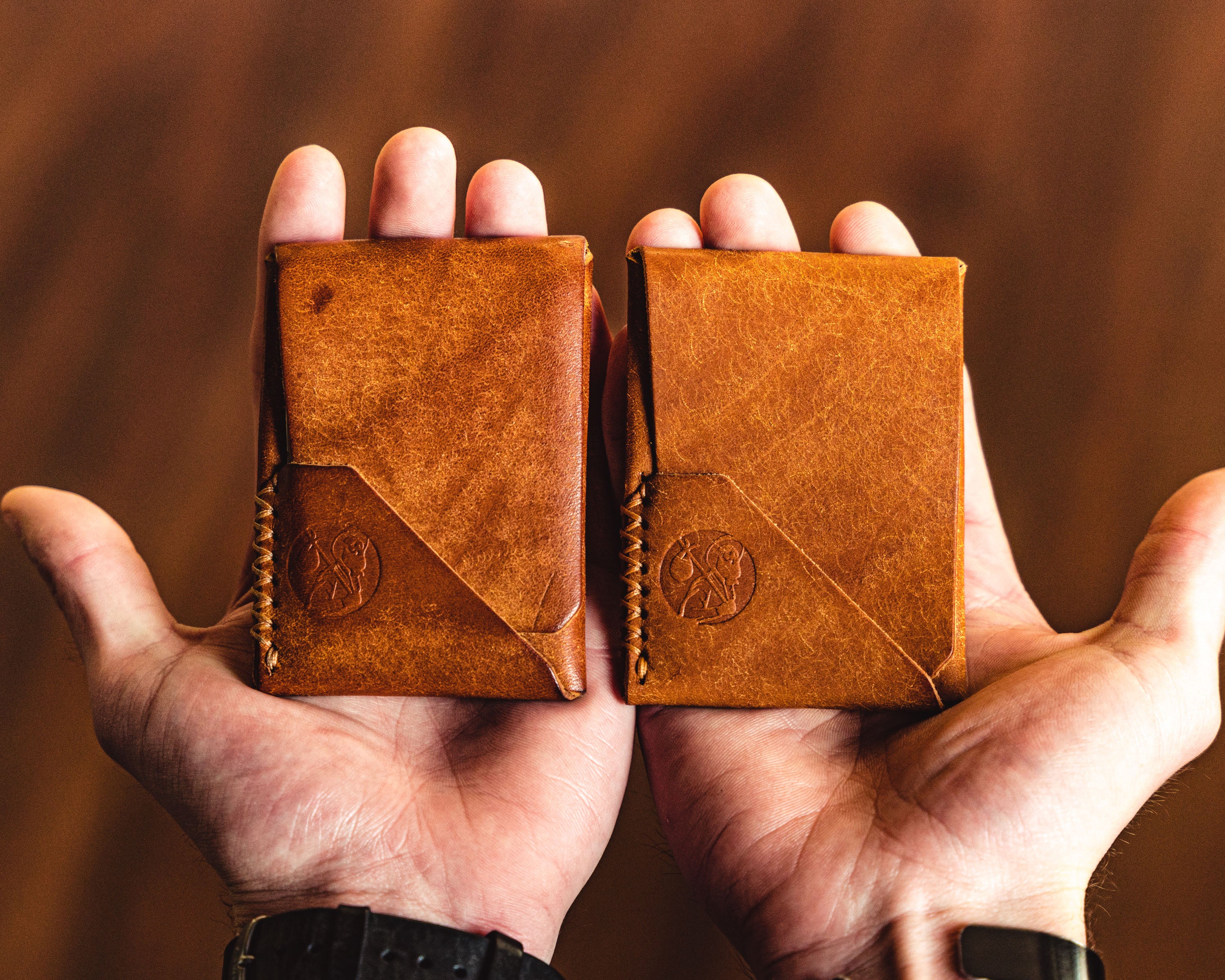 Two Carry Commission / Open Sea Leather Topsider Minis being held side by side to show a patina comparison between a new and a used wallet