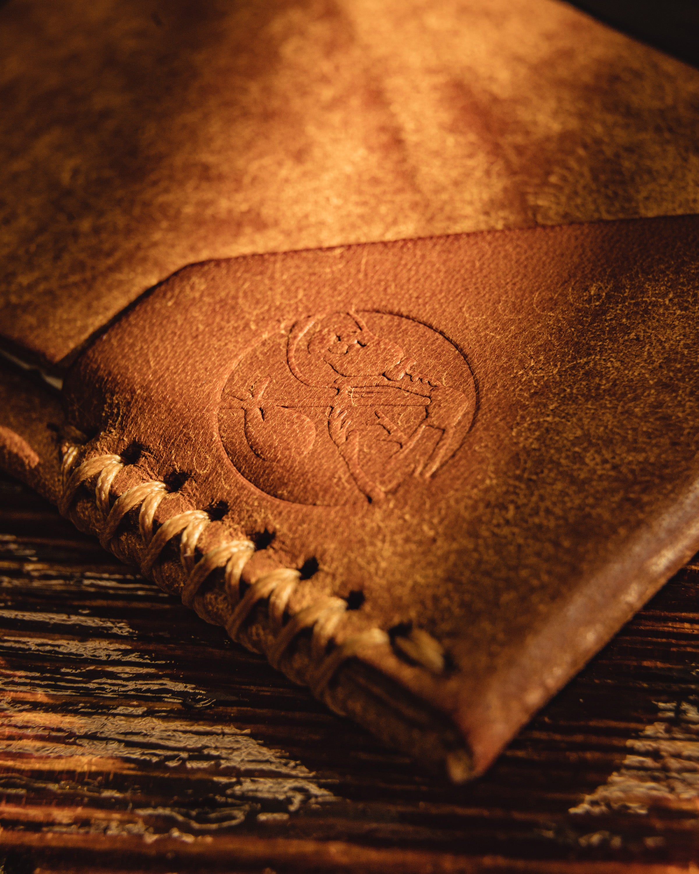 Carry Commission / Open Sea Leather Topsider Mini close up view of Carry Commission Logo Stamp on wallet on wooden background