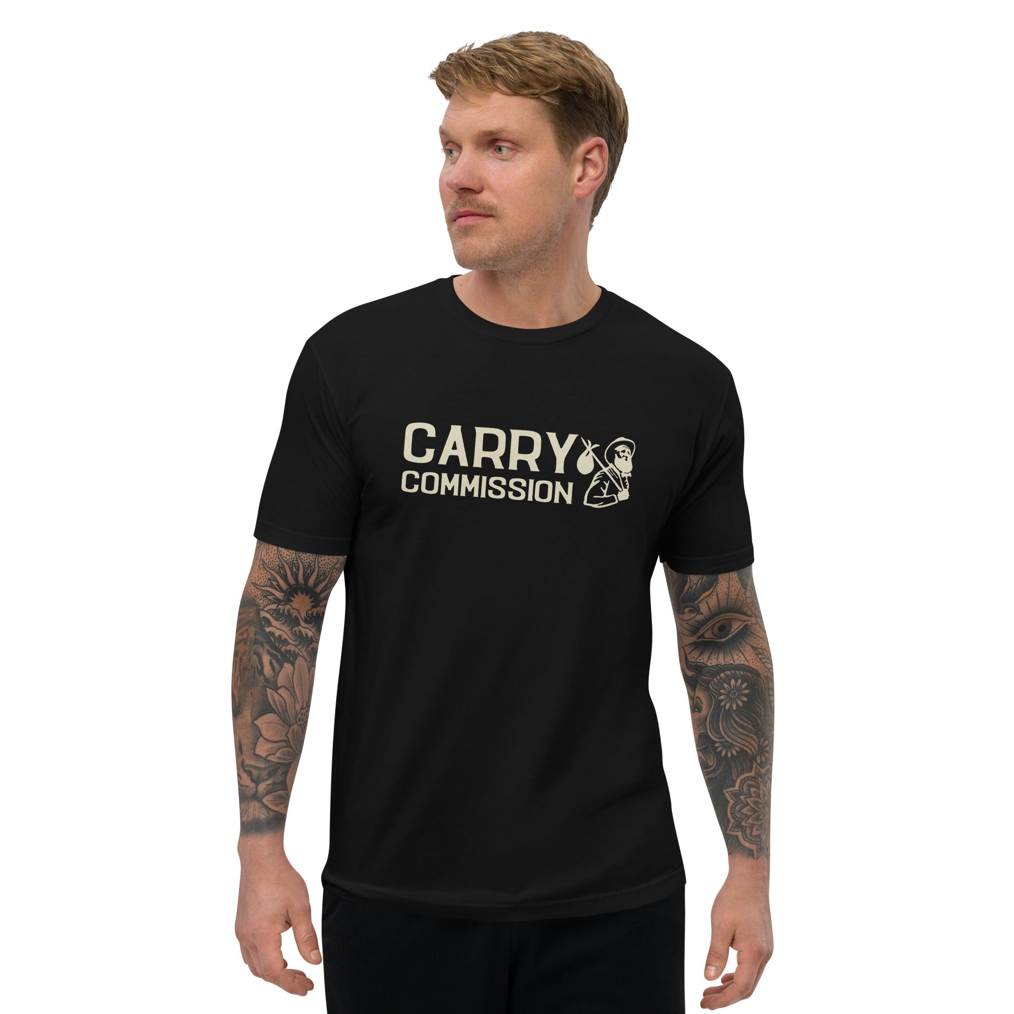 Front side of black Carry Commission T-shirt sporting the lettering and man holding bindle on shoulder being modeled by tattooed male.